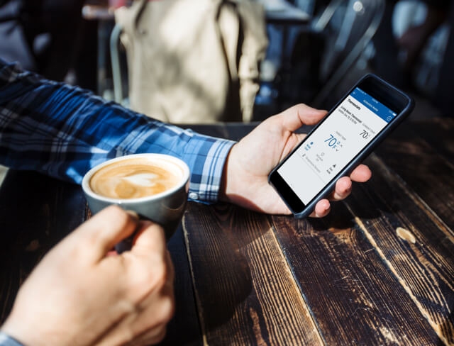 Person using ADT home security app and drinking coffee